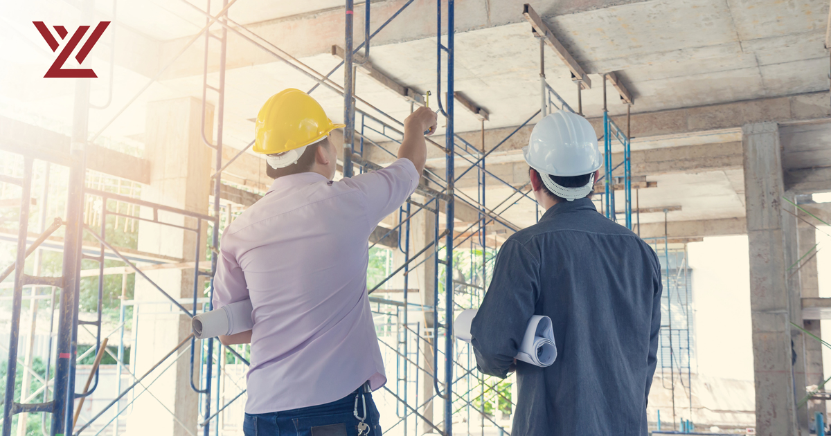 Two men in hardhats looks at a construction site