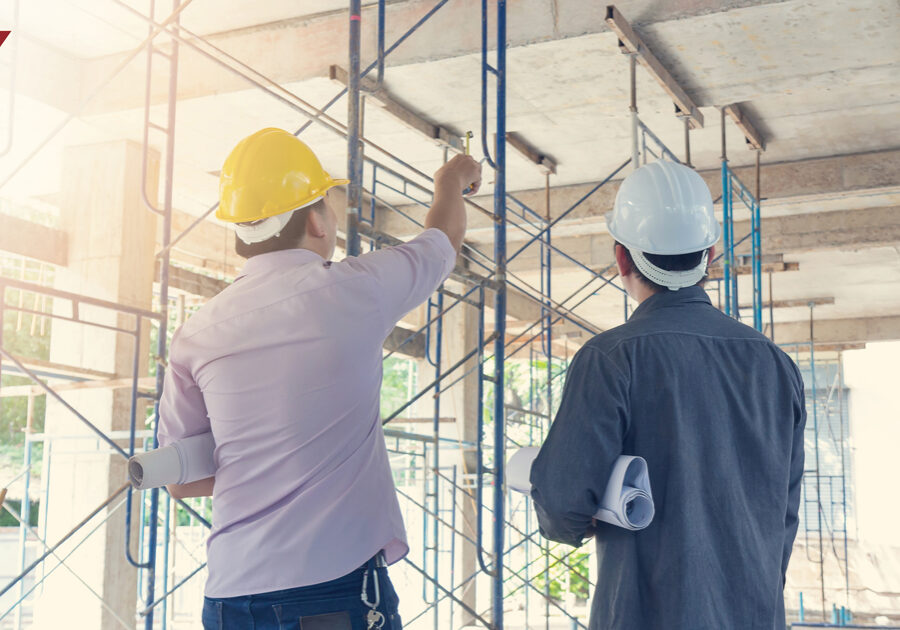 Two men in hardhats looks at a construction site