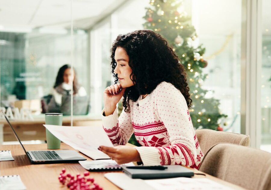 Woman in a holiday sweater looks at papers in the office