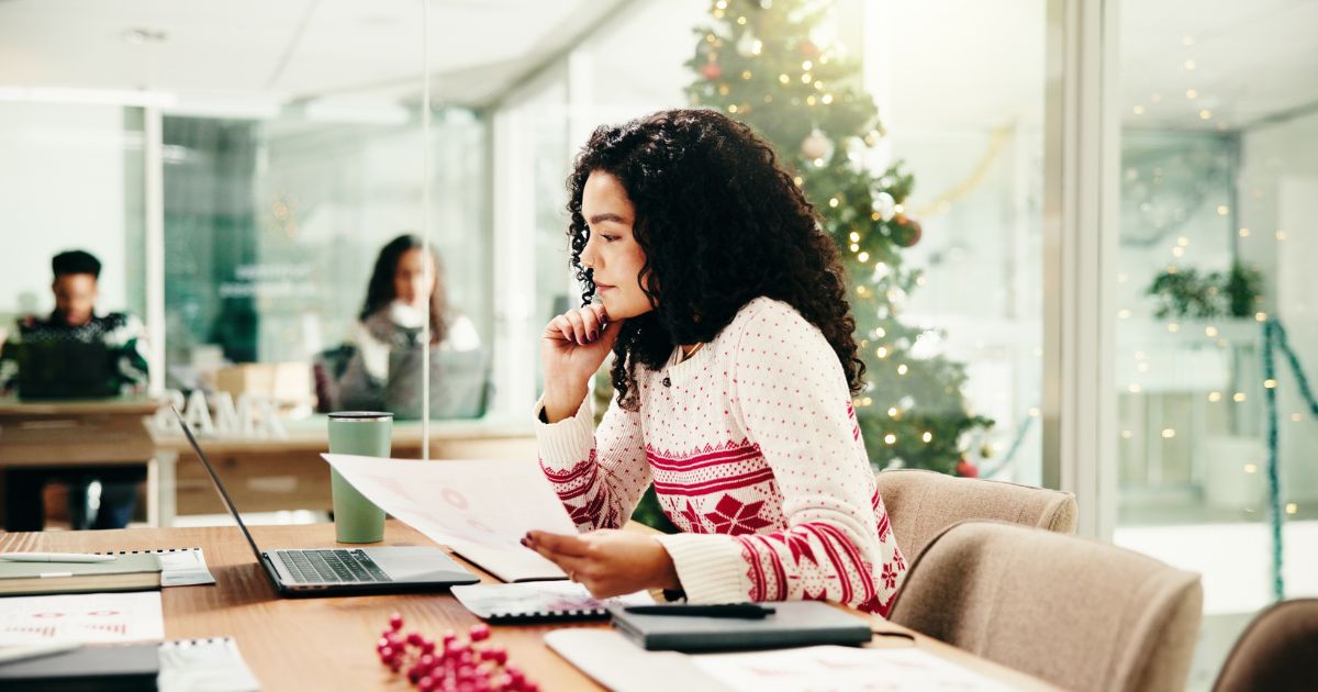 Woman in a holiday sweater looks at papers in the office